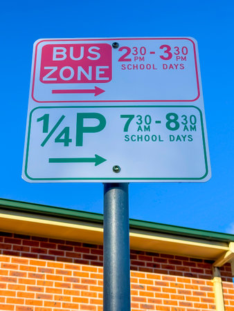 Photograph of a red and green text School Bus Zone and Parking sign against a vibrant bright blue sky on a sunny day.の写真素材