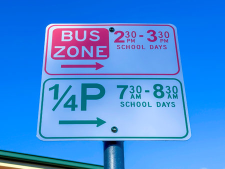 Photograph of a red and green text School Bus Zone and Parking sign against a vibrant bright blue sky on a sunny day.の写真素材