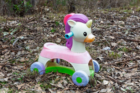 Photograph of a small plastic colourful unicorn toy that has been discarded on the ground on dry tree leaves in a remote forest.の写真素材