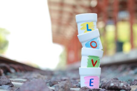 Love wording on small cup stacking with blur background of the Railway in train station.の写真素材