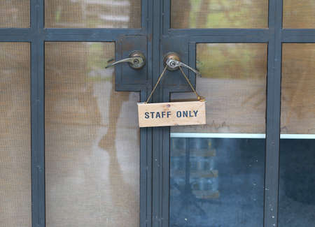 Staff only sign hanging on handle on steel door