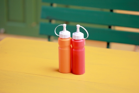 bottle of chili and tomato sauce on yellow tableの写真素材