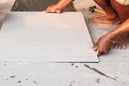 Labor installing tile floor for new house buildingの写真素材