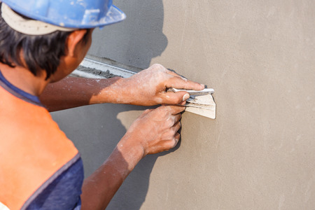 plasterer concrete worker at wall of house constructionの写真素材