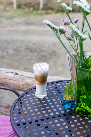 Caramel cappuccino coffee glass on table in cafeの写真素材