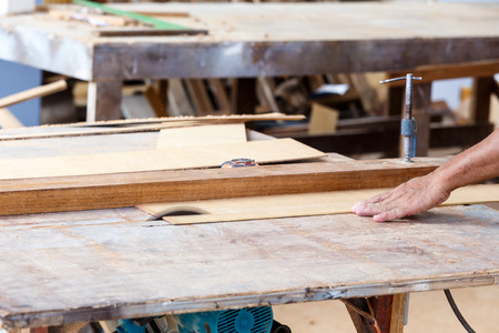 carpenter use saw cut wood for make new furnitureの写真素材