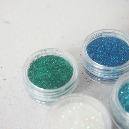 Blue and green glitter in clear jars on a white background. Top view.の写真素材