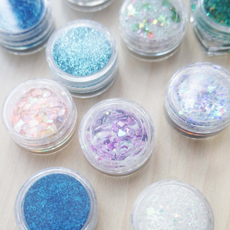 Close up of glitter in clear bottles on wooden background. Beauty and fashion concept.の写真素材