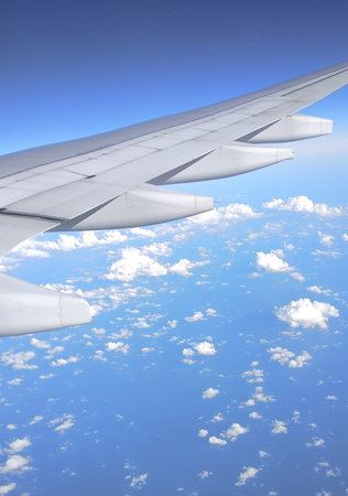 Airplane wing on blue sky with white clouds. Travel concept.の写真素材