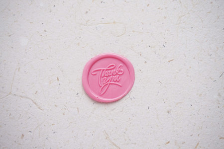 Pink wax seal on white paper background. Top view. Copyspace.の写真素材