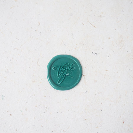 Close up of a green wax seal stamp on a white paper backgroundの写真素材