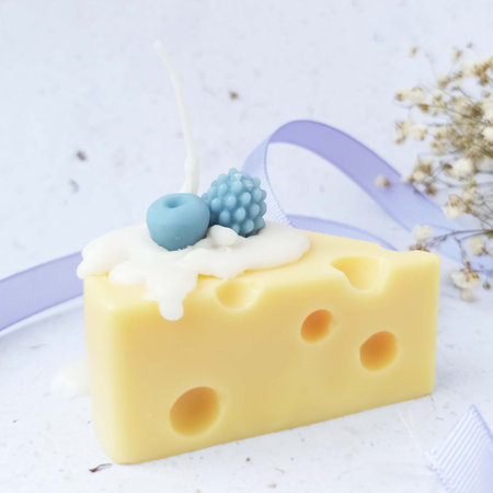 Cheese cake candle decorated with blueberries and a blue ribbon on a white backgroundの写真素材