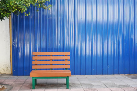 Bench in front of a blue metal wall with space for text.の写真素材