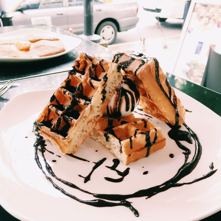 Belgian waffle with chocolate topping on white plateの写真素材