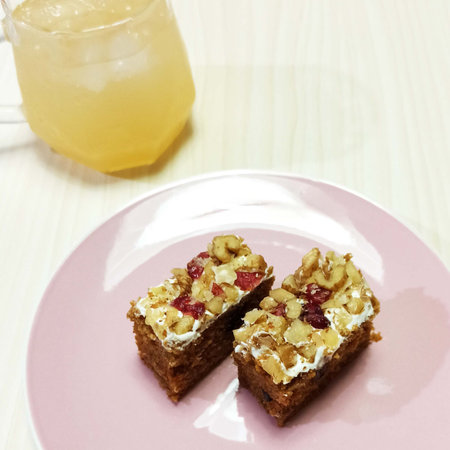 Two pieces of cake with walnuts on a pink plate and a glass of lemonadeの写真素材
