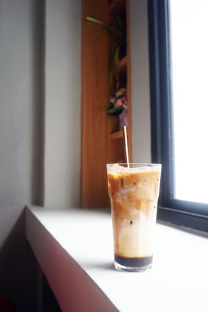 Iced coffee with milk in a glass on the windowsill.の写真素材