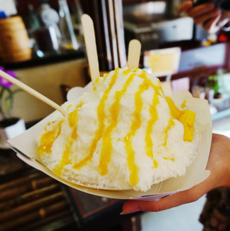 Ice cream with mango topping on white plate in hand of woman.の写真素材