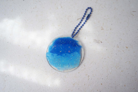 Blue pendant on a white background with a shadow from the sunの写真素材