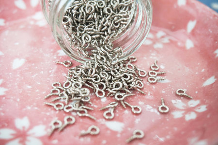 Metal screw in glass jar on pink background. Selective focus.の写真素材