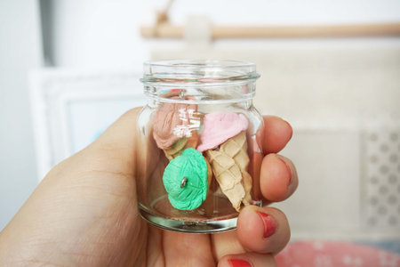 Hand holding a glass jar with marshmallows in the shape of a unicornの写真素材