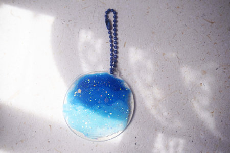 Blue glass pendant on a white background with shadow from the sunの写真素材