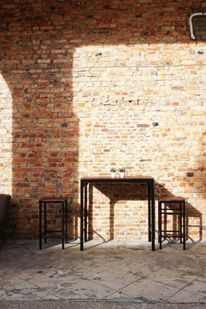 Wooden table and chairs in the room with brick wall background.