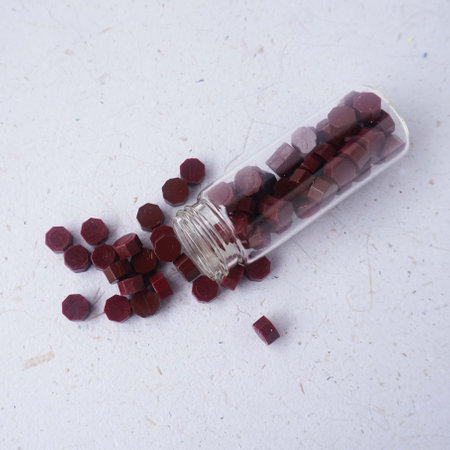Close up of red wax sealing bead in a glass bottle on a white background