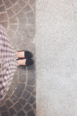 Female legs in black shoes on the background of the stone pavement.の写真素材