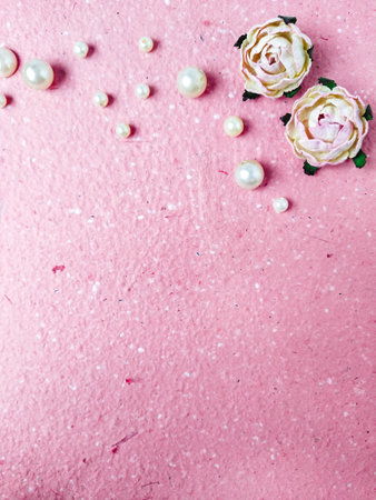Pink paper background with pearls and roses. Flat lay, top view.の写真素材