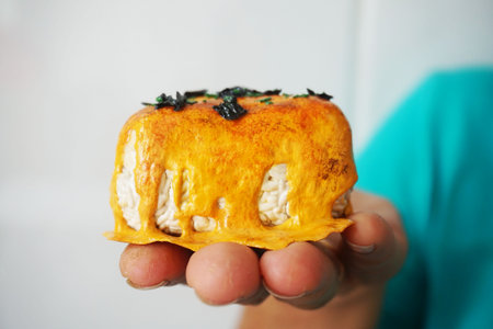 Close-up of a person holding a freshly baked cake on a white background