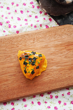 Puff pastry with black crumbs on a wooden cutting board.