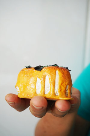 Close up of a man holding a piece of cake with cheese on top