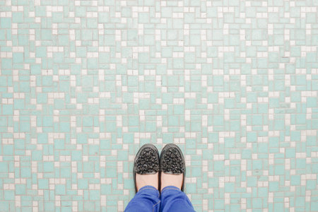 Selfie of woman's feet in sneakers on a tile background.