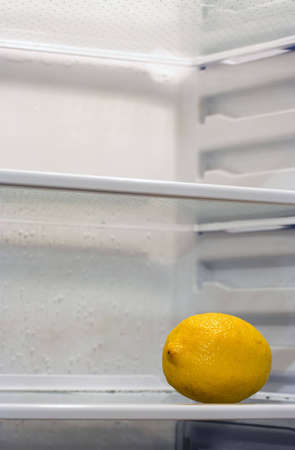 A lemon inside fridge, sitting alone on the shelf. Copyspace provided.の写真素材