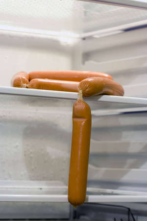 A bunch of sausages inside fridge, sitting alone on the shelf. Copyspace provided.の写真素材