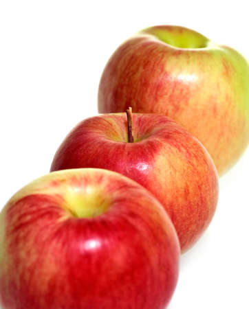 Three apples placed in a row. Focus on the middle one.