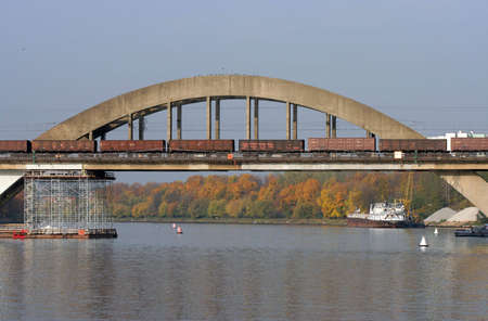 The railway bridge over the river with freight train passing by.の写真素材