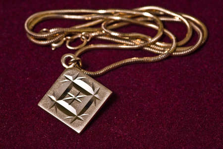 Golden pendant with chain on velvet background.の写真素材