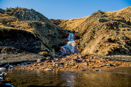 Orange waterfall from below, framed by rock, in icelandの写真素材