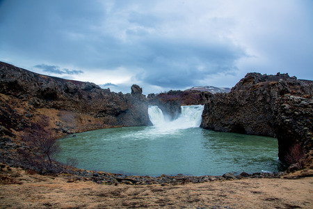 Green waterfall with basalt rock in beautiful icelandic natureの写真素材