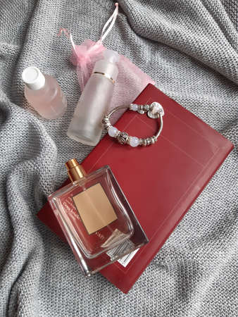 a table with a silver cloth on it, a book, cosmetics in bottles and perfume