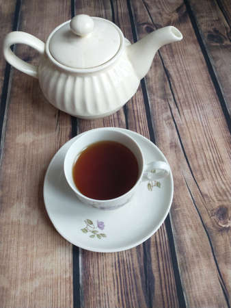 on the table a white porcelain teapot and a white cup of teaの写真素材