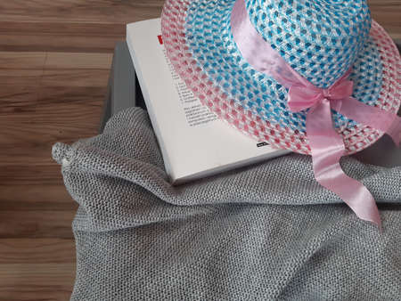 a casually thrown gray sweater on it lies a book and a blue hat with a bowの写真素材