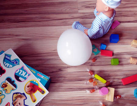 colored blocks scattered on the floor, a balloon, a doll and a game for childrenの写真素材