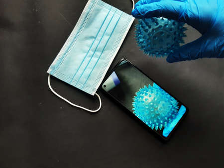 the image related to covid shows a hand in a protective glove, a mask and a ball symbolizing the virus.の写真素材