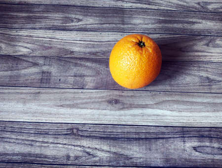 there is 1 orange on the wooden tableの写真素材