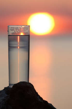 thin glass with water on sunset backgroundの写真素材