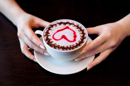 hands hold cup of coffee on tableの写真素材