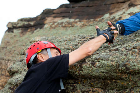 rock climber take hand of friend