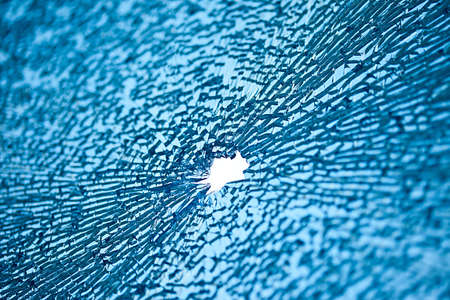 blue glass with many cracks and hole in middleの写真素材